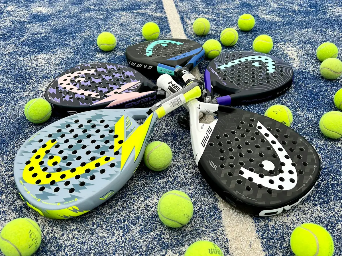 Five padel rackets laid in a circle on a blue padel court, surrounded by yellow balls
